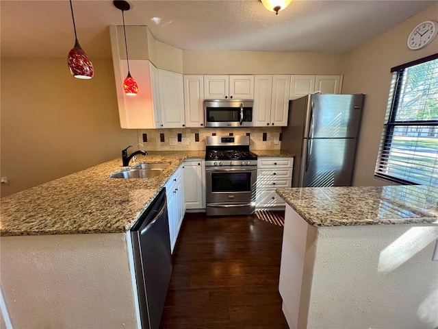 kitchen featuring white cabinetry, sink, kitchen peninsula, decorative light fixtures, and appliances with stainless steel finishes