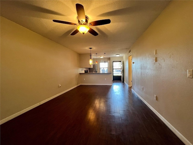 unfurnished living room featuring ceiling fan, dark hardwood / wood-style flooring, and a textured ceiling