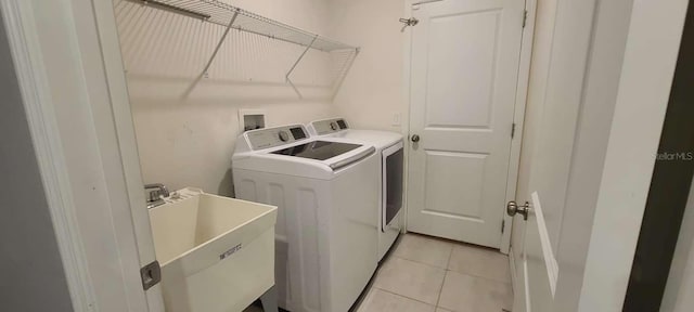 laundry room with washing machine and clothes dryer, sink, and light tile patterned floors