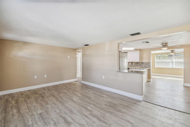 unfurnished living room with light hardwood / wood-style floors and a textured ceiling