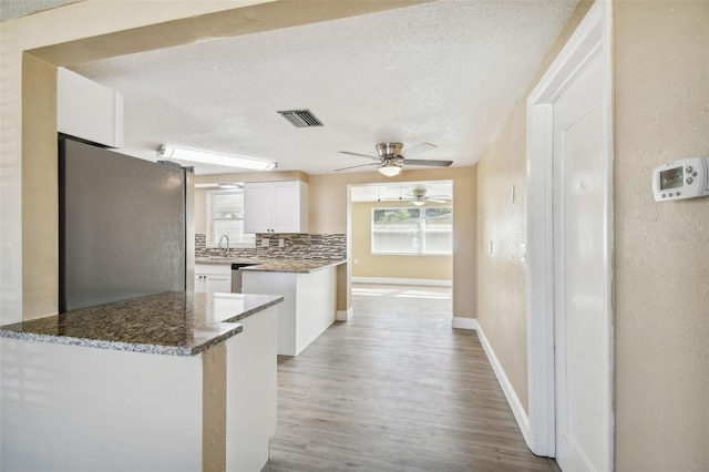 kitchen featuring stainless steel fridge, light wood-type flooring, backsplash, a textured ceiling, and white cabinets