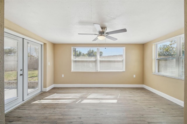 unfurnished room featuring light hardwood / wood-style floors, a textured ceiling, a wealth of natural light, and french doors