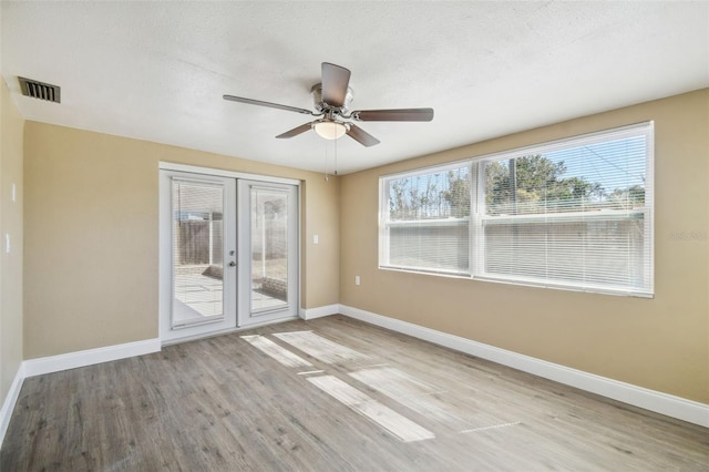 unfurnished room with ceiling fan, light hardwood / wood-style flooring, a wealth of natural light, and french doors