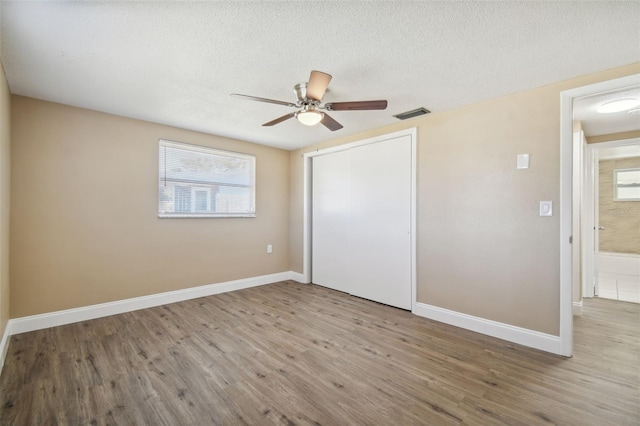 unfurnished bedroom with ceiling fan, a closet, a textured ceiling, and light wood-type flooring