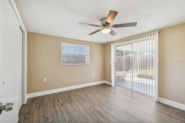 unfurnished bedroom featuring access to exterior, a textured ceiling, ceiling fan, hardwood / wood-style flooring, and a closet