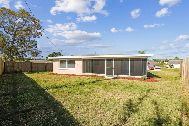 back of property with a yard and a sunroom