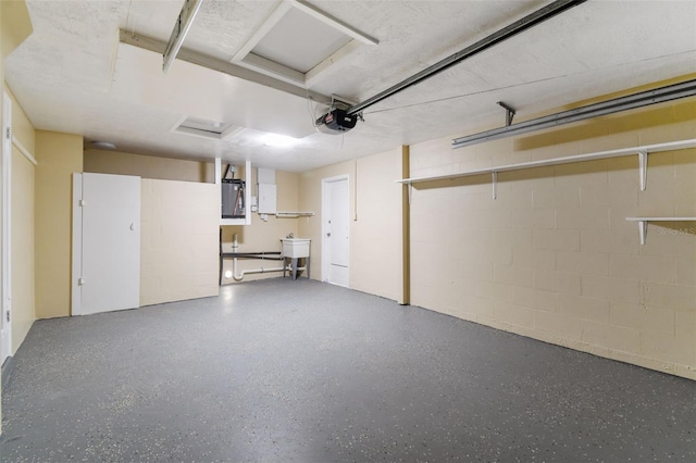 garage featuring electric panel, sink, and a garage door opener