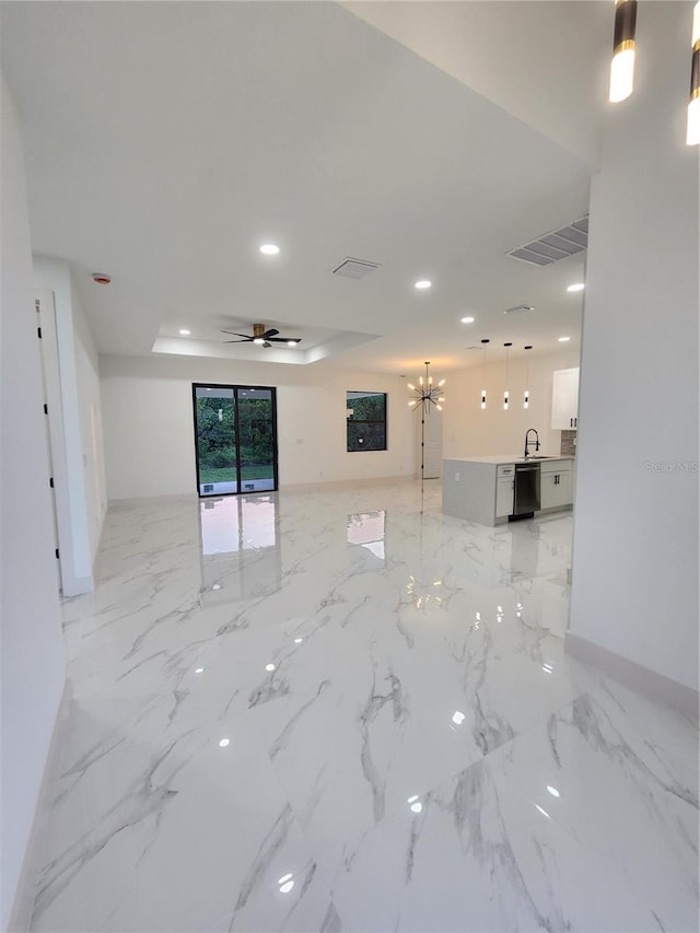 spare room with a tray ceiling and ceiling fan with notable chandelier