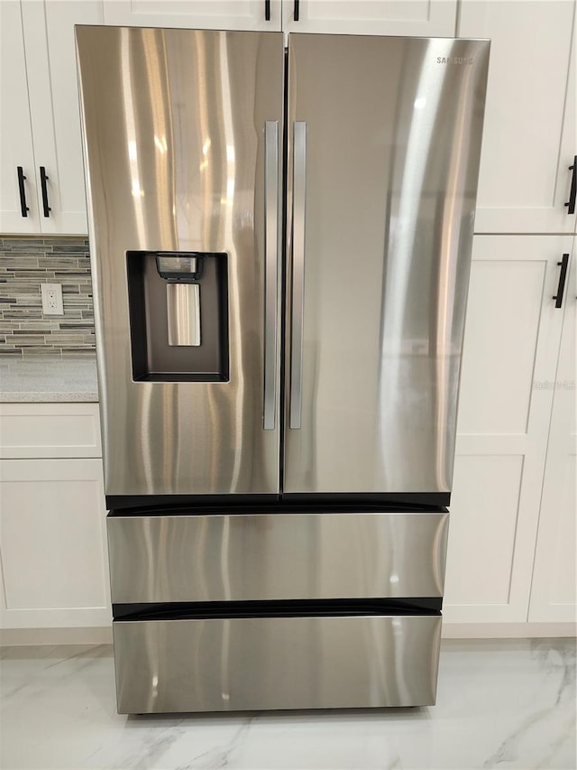 details featuring light stone countertops, stainless steel fridge with ice dispenser, backsplash, and white cabinetry