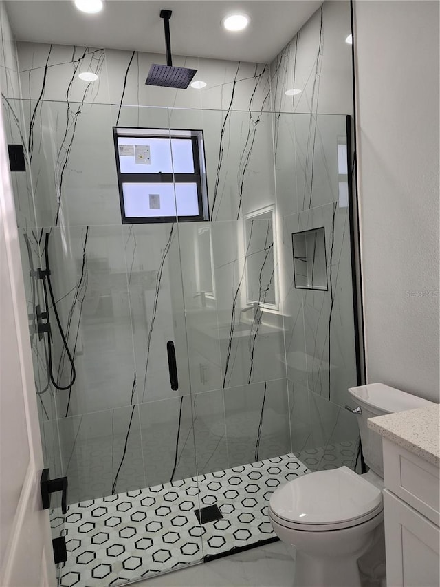 bathroom featuring a shower with door, vanity, and toilet