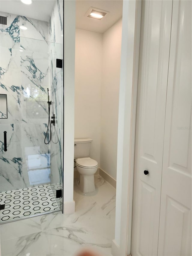 bathroom featuring toilet and a shower with shower door