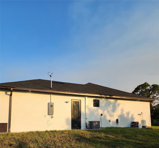 back of property featuring a lawn and cooling unit