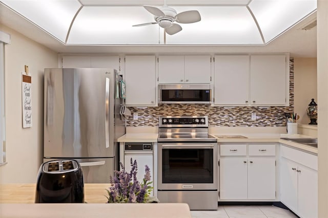 kitchen with decorative backsplash, white cabinetry, stainless steel appliances, and light tile patterned floors