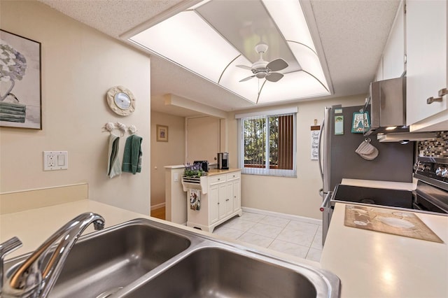 kitchen featuring ceiling fan, white cabinetry, sink, and light tile patterned floors