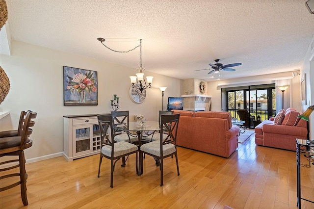 dining area featuring a textured ceiling, light hardwood / wood-style flooring, and ceiling fan with notable chandelier