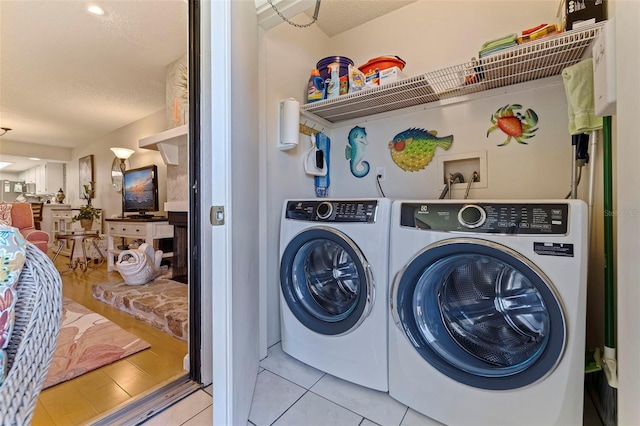 washroom featuring light tile patterned flooring, washer and dryer, and a textured ceiling