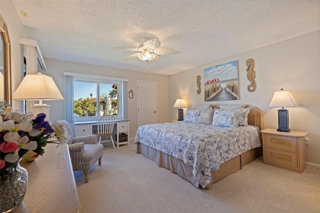 bedroom with ceiling fan, light colored carpet, and a textured ceiling