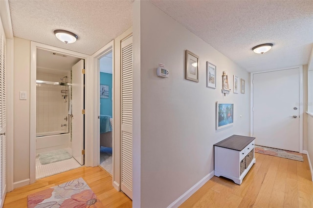 hallway featuring a textured ceiling and light hardwood / wood-style floors