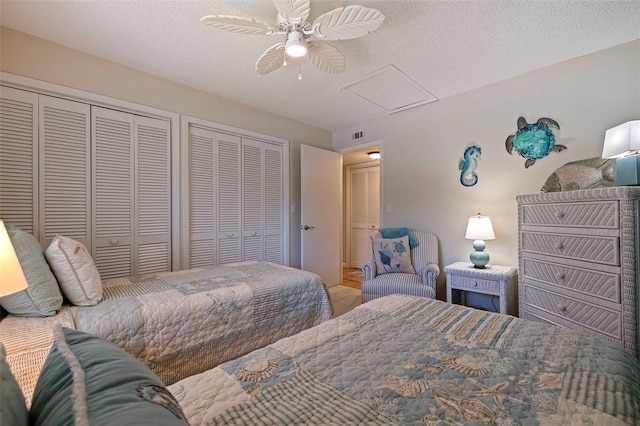 bedroom featuring ceiling fan, a textured ceiling, and multiple closets