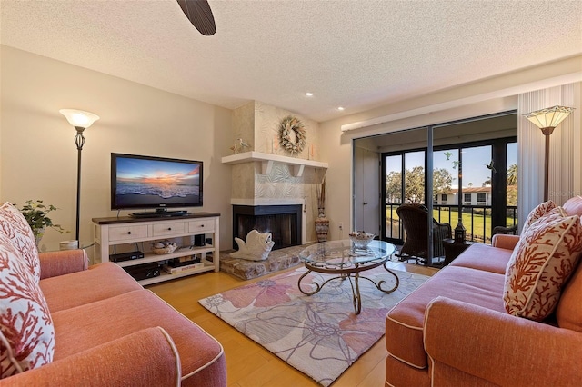 living area featuring recessed lighting, a textured ceiling, a large fireplace, and wood finished floors