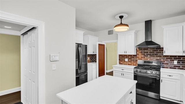 kitchen featuring tasteful backsplash, gas stove, wall chimney range hood, white cabinetry, and fridge