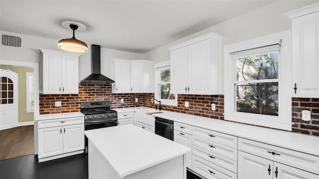 kitchen with black appliances, wall chimney exhaust hood, a healthy amount of sunlight, and white cabinets