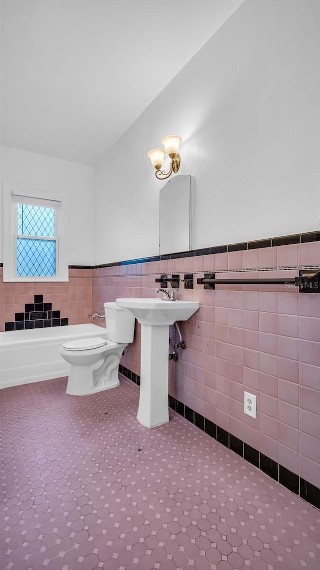 bathroom featuring toilet, tile walls, and sink