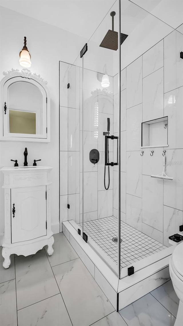 bathroom featuring a shower with door, vanity, and toilet