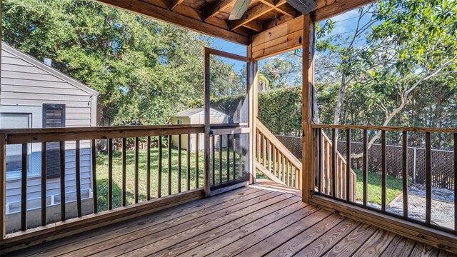 wooden terrace featuring ceiling fan and a storage shed