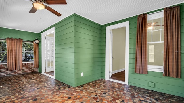 interior space with ceiling fan and wood walls