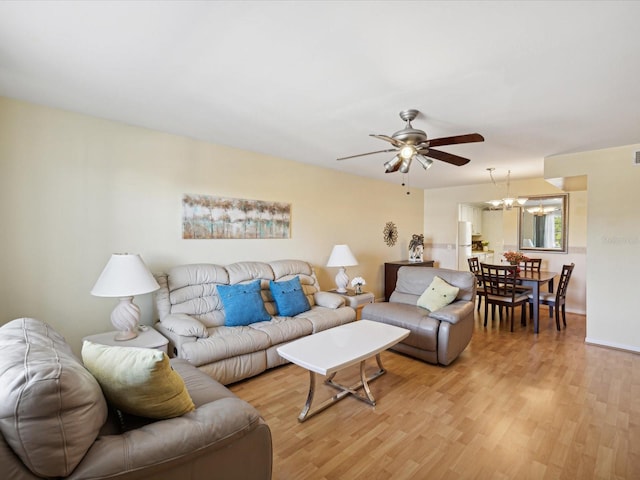 living room with ceiling fan with notable chandelier and light hardwood / wood-style flooring