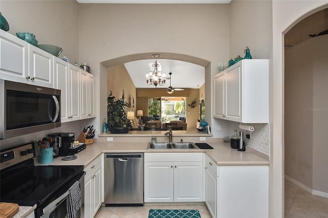 kitchen featuring stainless steel appliances, sink, light tile patterned floors, white cabinets, and hanging light fixtures