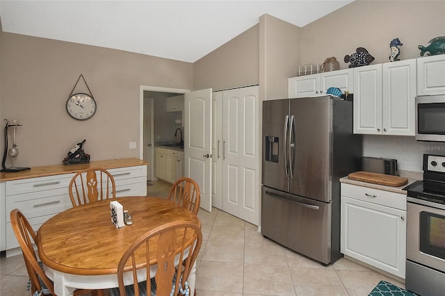 kitchen with decorative backsplash, white cabinetry, stainless steel appliances, and light tile patterned floors