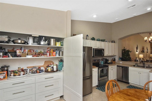 kitchen with white cabinets, sink, stainless steel appliances, and a chandelier