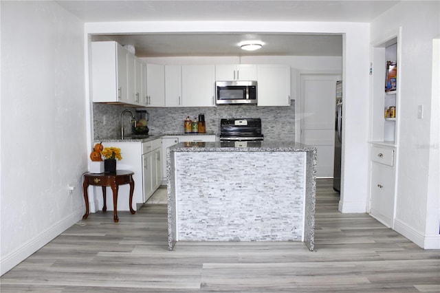 kitchen featuring decorative backsplash, light stone countertops, white cabinets, and stainless steel appliances