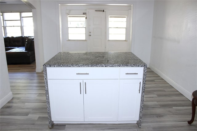 kitchen with hardwood / wood-style floors, a center island, white cabinetry, and dark stone countertops