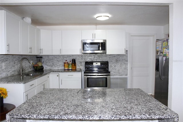 kitchen featuring dark stone countertops, white cabinetry, sink, and stainless steel appliances