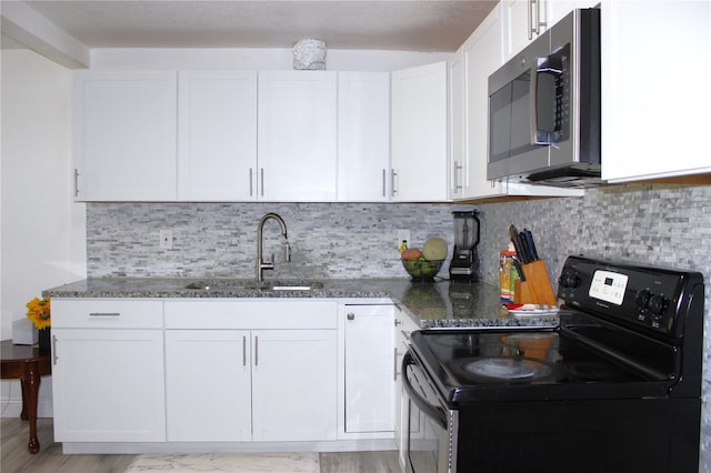 kitchen with sink, black electric range oven, dark stone counters, light hardwood / wood-style floors, and white cabinets