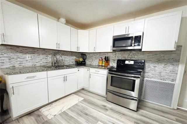 kitchen with light wood-type flooring, stainless steel appliances, white cabinetry, and sink