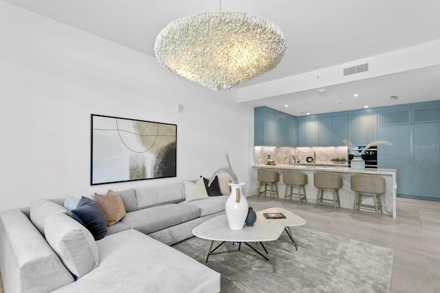 living room featuring light hardwood / wood-style flooring, an inviting chandelier, and sink