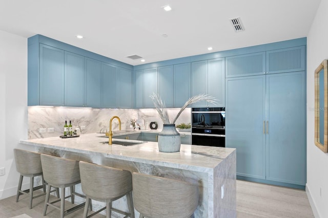 kitchen featuring light wood-type flooring, kitchen peninsula, and a breakfast bar area