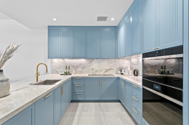 kitchen with black electric cooktop, decorative backsplash, sink, and blue cabinets