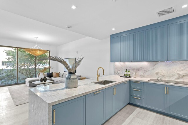 kitchen with sink, black electric cooktop, tasteful backsplash, decorative light fixtures, and kitchen peninsula