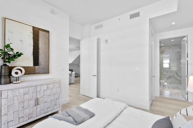 bedroom featuring ensuite bathroom and light hardwood / wood-style floors