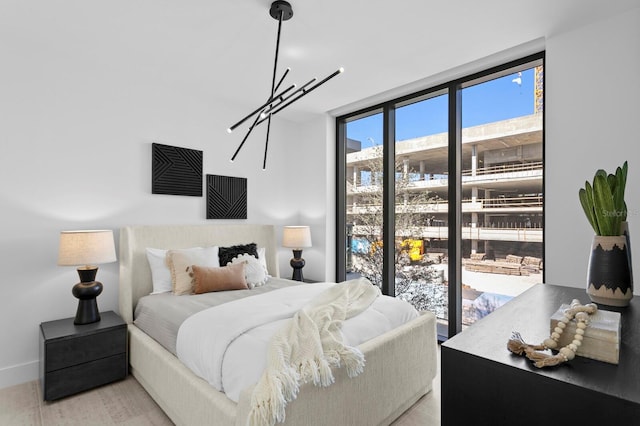 bedroom featuring access to exterior, light hardwood / wood-style flooring, and an inviting chandelier