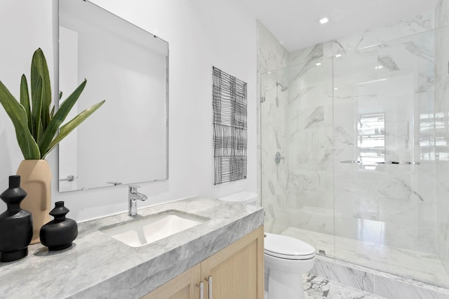 bathroom with a shower with door, vanity, and toilet