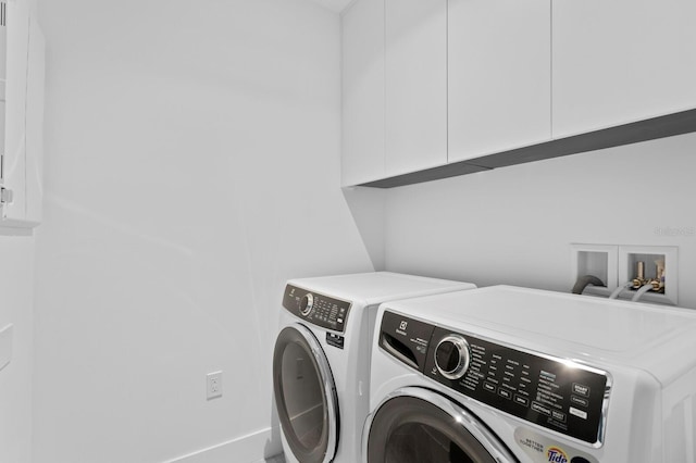 washroom with washing machine and clothes dryer and cabinets