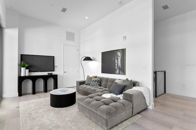 living room with high vaulted ceiling and light hardwood / wood-style flooring