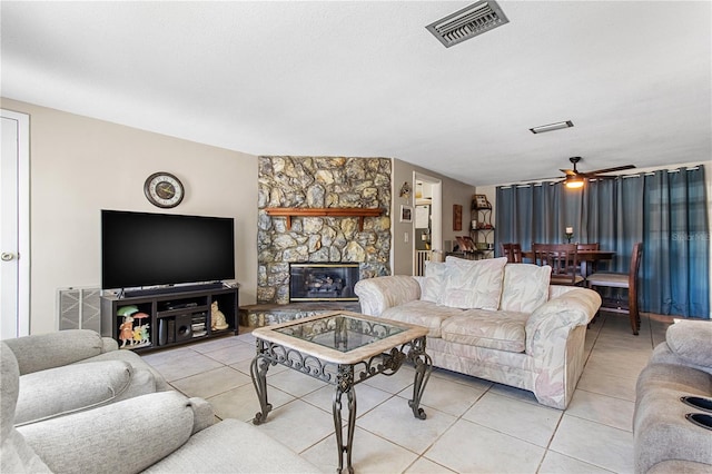 tiled living room featuring a fireplace, a textured ceiling, and ceiling fan