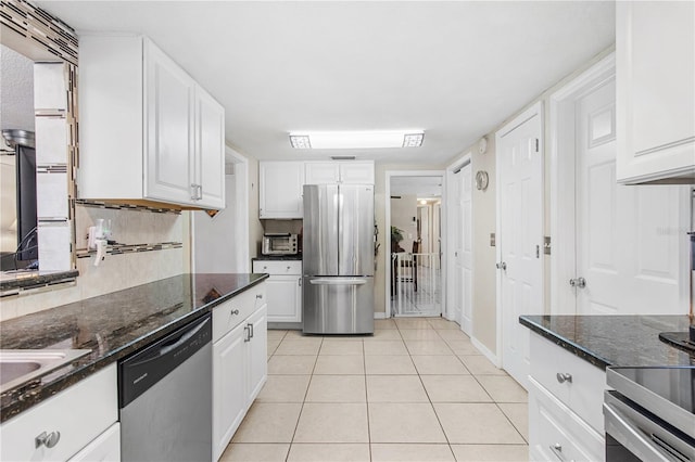 kitchen with dark stone countertops, white cabinetry, and stainless steel appliances